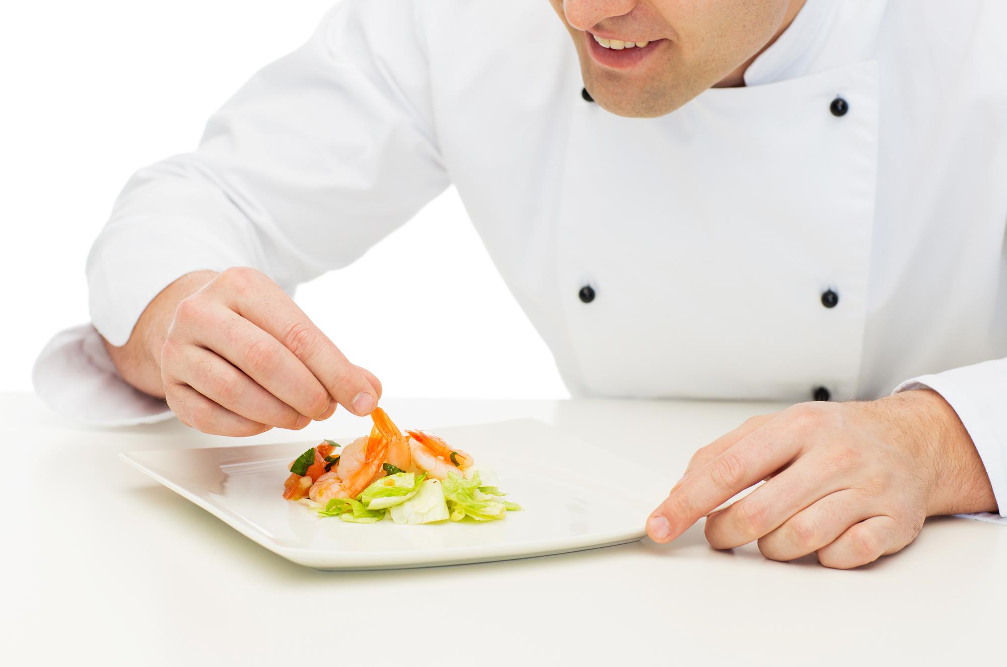 Instructor preparing a modern dish in a compact professional kitchen